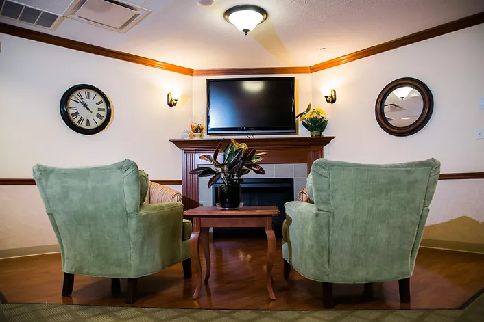 Inpatient living room with TV, fireplace and green chairs