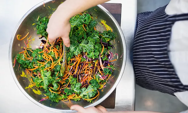 Close up of cook making a salad for residents