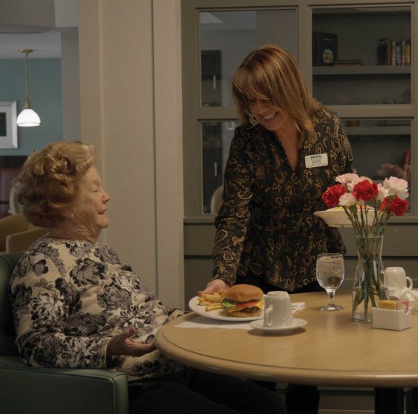Brentwood Staff speaking with a female senior at a dinner table