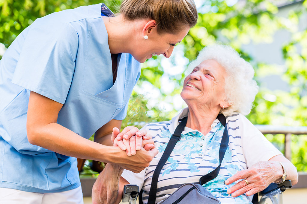 Nurse assisting elderly woman outside