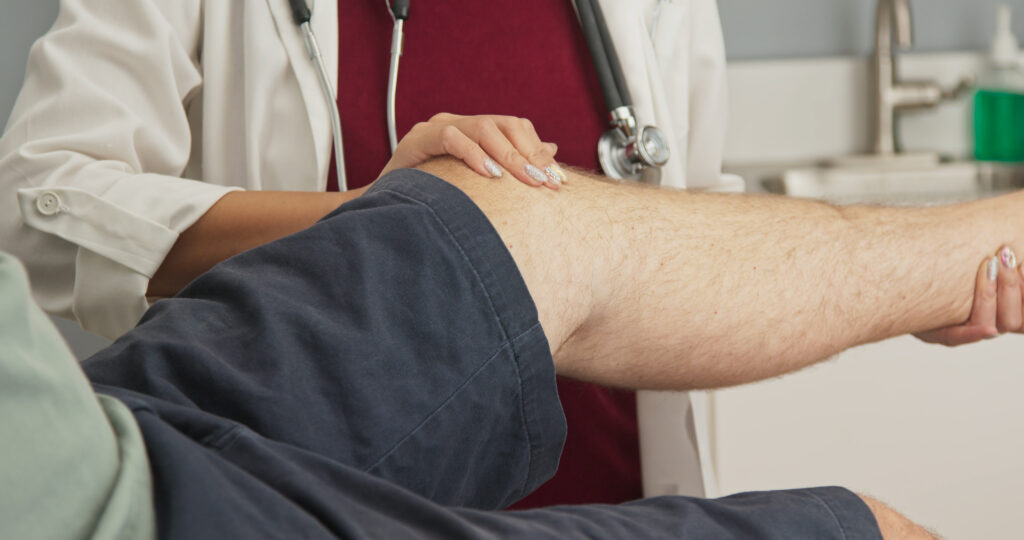 Close up on physical therapist or doctor manipulating knee of patient